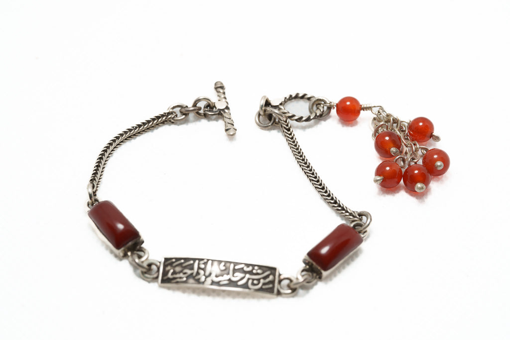 Silver bracelet with red beads on a white background